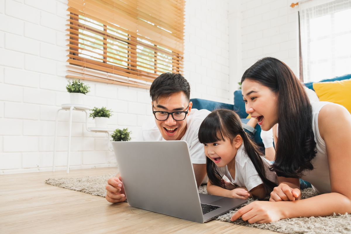 Asian family using laptop computer to surf internet / online shopping, happy family with technology concept